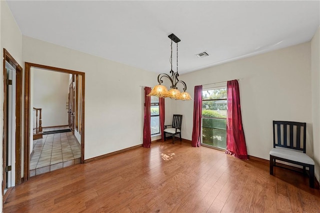 unfurnished dining area with hardwood / wood-style floors and a notable chandelier