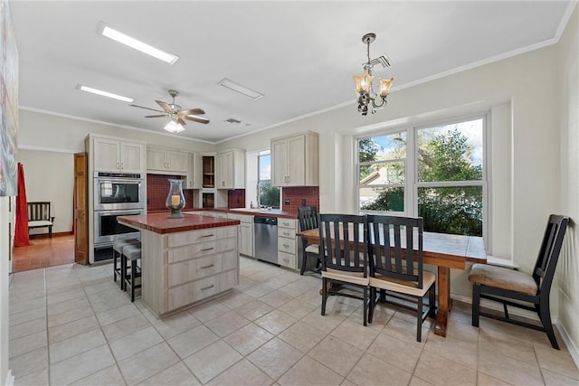 kitchen featuring butcher block counters, a center island, hanging light fixtures, crown molding, and appliances with stainless steel finishes