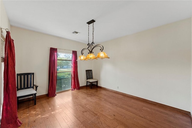 dining space featuring wood-type flooring and an inviting chandelier