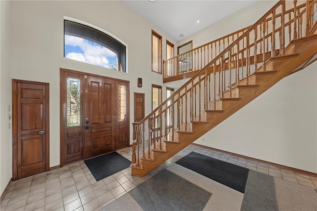 entrance foyer featuring a towering ceiling and light tile patterned floors