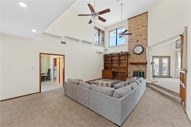 carpeted living room with ceiling fan, a healthy amount of sunlight, and a high ceiling