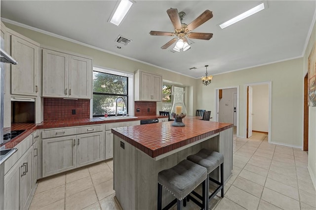 kitchen featuring a center island, sink, decorative backsplash, ornamental molding, and a kitchen bar