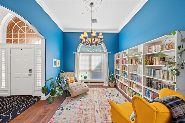 living area featuring ornamental molding, wood-type flooring, and an inviting chandelier