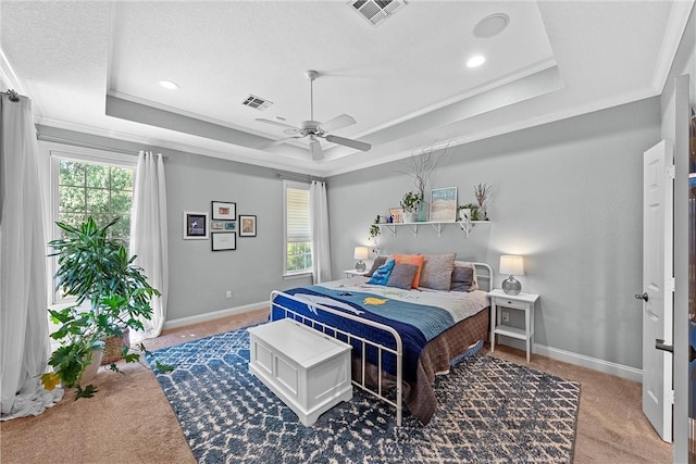 bedroom featuring ceiling fan, a raised ceiling, carpet floors, a textured ceiling, and ornamental molding