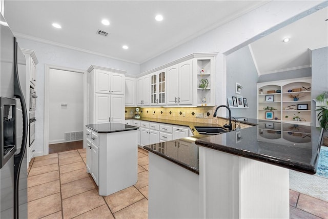 kitchen featuring kitchen peninsula, decorative backsplash, dark stone counters, sink, and white cabinetry