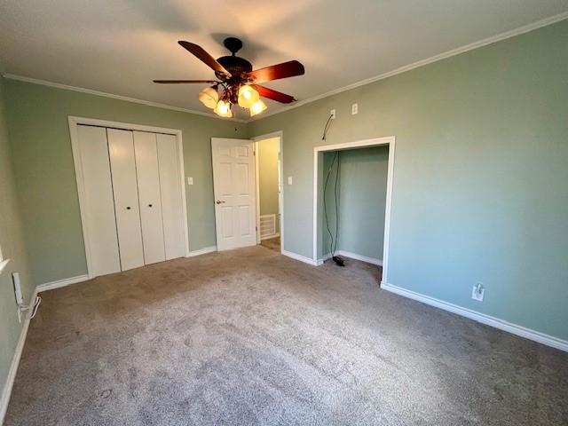 unfurnished bedroom with crown molding, carpet flooring, ceiling fan, and a closet