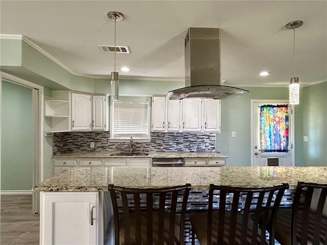 kitchen with pendant lighting, sink, light stone counters, white cabinets, and island exhaust hood