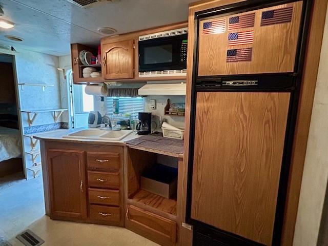 kitchen featuring sink, fridge, and black microwave