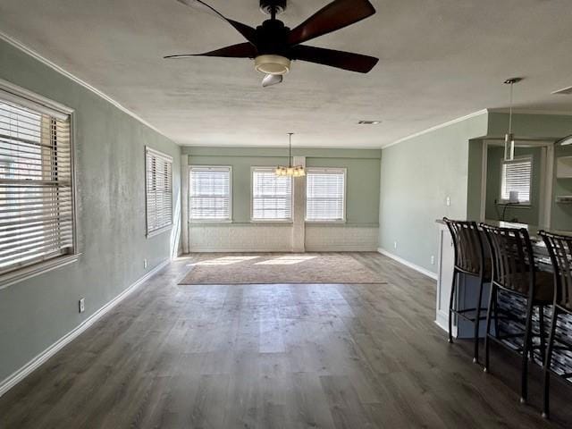 interior space with dark wood-type flooring, crown molding, and ceiling fan with notable chandelier