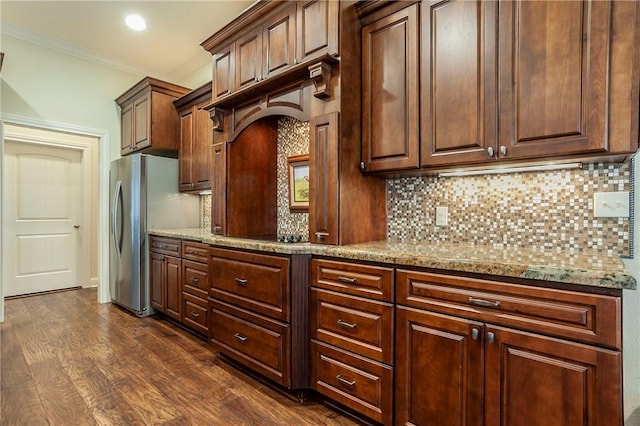 kitchen with stainless steel fridge, tasteful backsplash, light stone counters, crown molding, and dark hardwood / wood-style floors