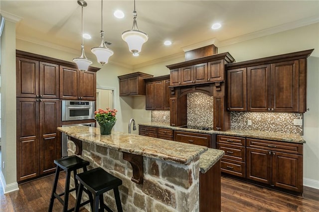 kitchen featuring dark brown cabinetry, stainless steel oven, dark hardwood / wood-style flooring, pendant lighting, and a center island with sink