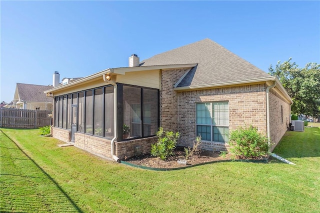 back of house with a lawn, a sunroom, and central AC unit