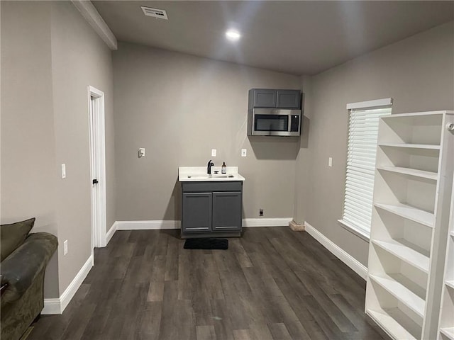 clothes washing area with sink and dark wood-type flooring