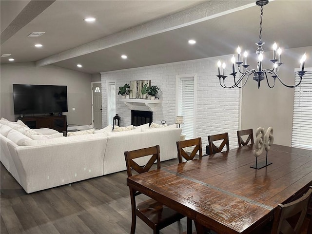 dining area featuring beam ceiling, a brick fireplace, brick wall, dark hardwood / wood-style floors, and a notable chandelier