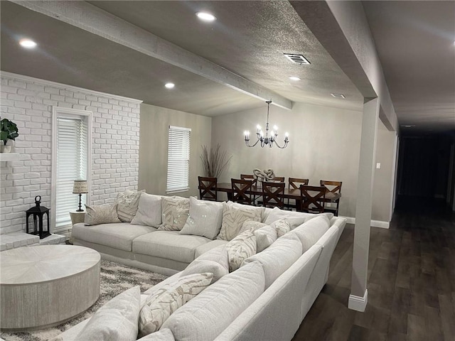 living room featuring vaulted ceiling with beams, a notable chandelier, dark hardwood / wood-style flooring, and brick wall