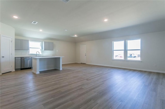 kitchen featuring a kitchen island, open floor plan, light countertops, gray cabinets, and dishwasher