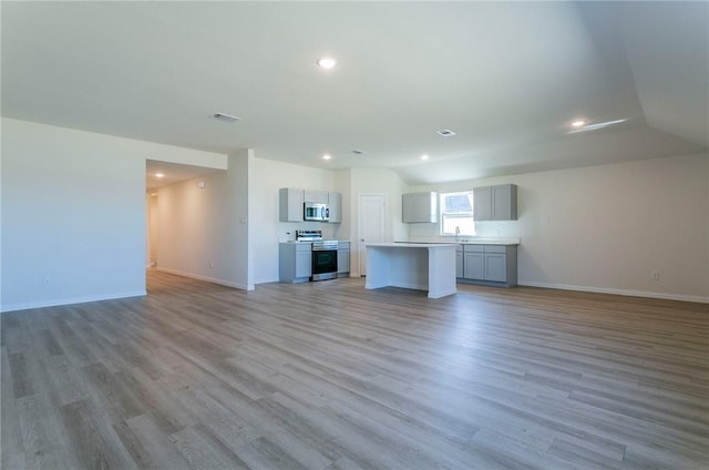 unfurnished living room featuring light wood finished floors, baseboards, and recessed lighting