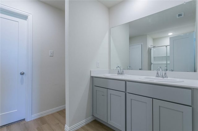 bathroom with visible vents, a sink, baseboards, and wood finished floors