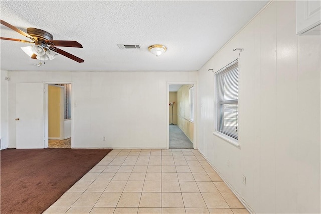 unfurnished room with a textured ceiling, light colored carpet, and ceiling fan