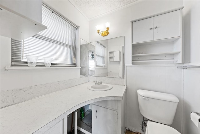 bathroom featuring a textured ceiling, vanity, toilet, and ornamental molding