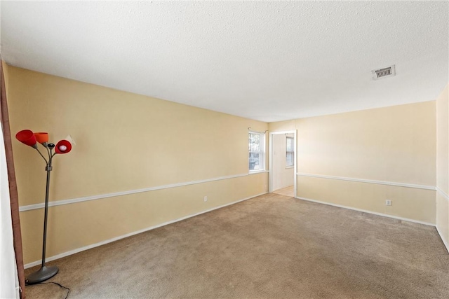 carpeted empty room featuring a textured ceiling