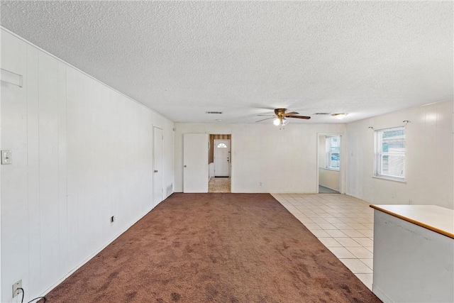 carpeted spare room featuring a textured ceiling and ceiling fan