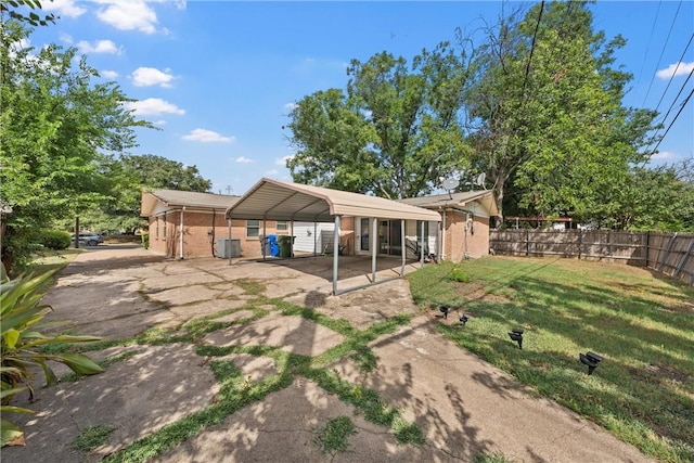 back of house with a carport, cooling unit, and a yard