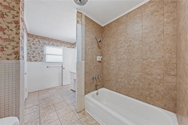 bathroom with tiled shower / bath combo, crown molding, a textured ceiling, toilet, and tile walls