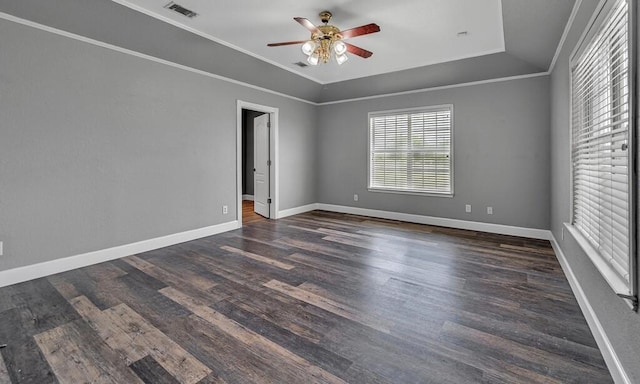 empty room featuring crown molding, visible vents, a ceiling fan, wood finished floors, and baseboards