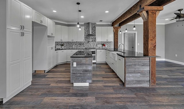 kitchen featuring white cabinets, pendant lighting, appliances with stainless steel finishes, and wall chimney range hood