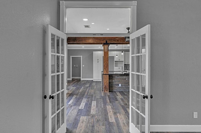 interior space with a barn door, dark wood-style flooring, visible vents, baseboards, and french doors