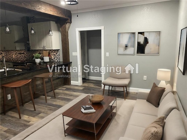 living area with baseboards, ornamental molding, and dark wood finished floors