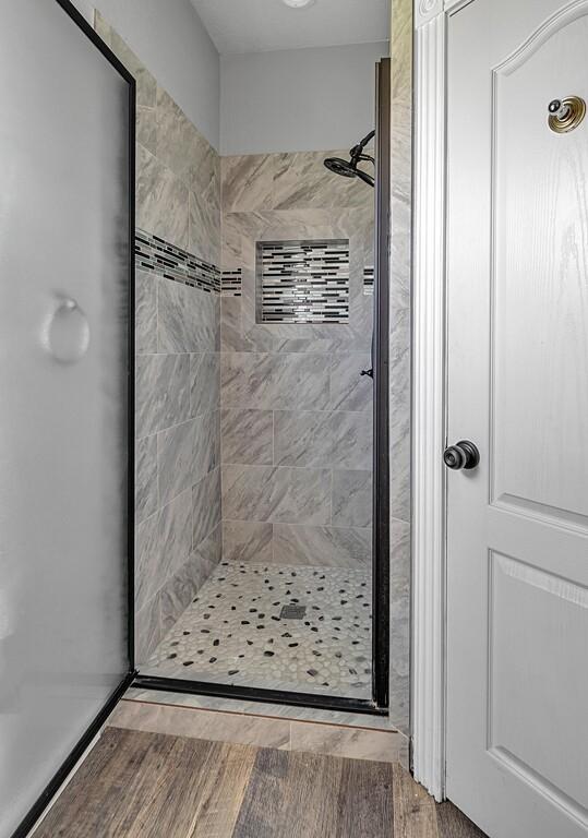 bathroom with a tile shower and hardwood / wood-style flooring