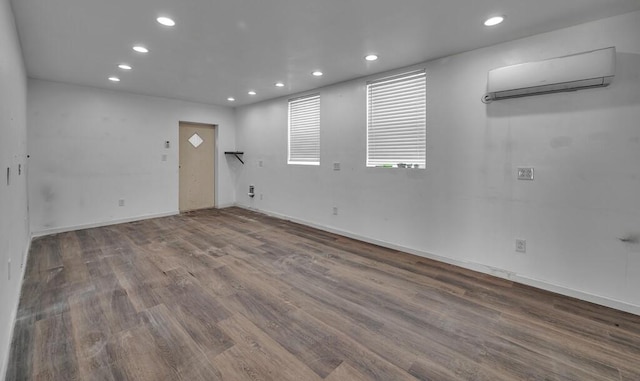 spare room featuring recessed lighting, baseboards, wood finished floors, and a wall mounted air conditioner