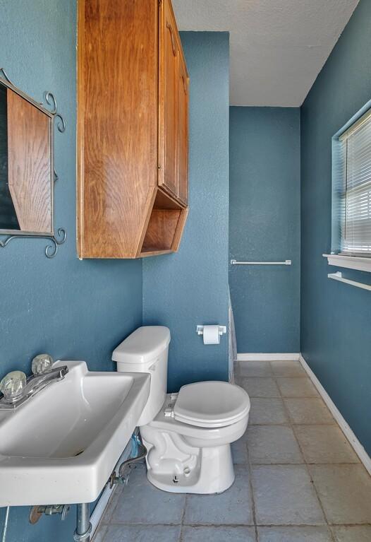 half bath with baseboards, a sink, and toilet