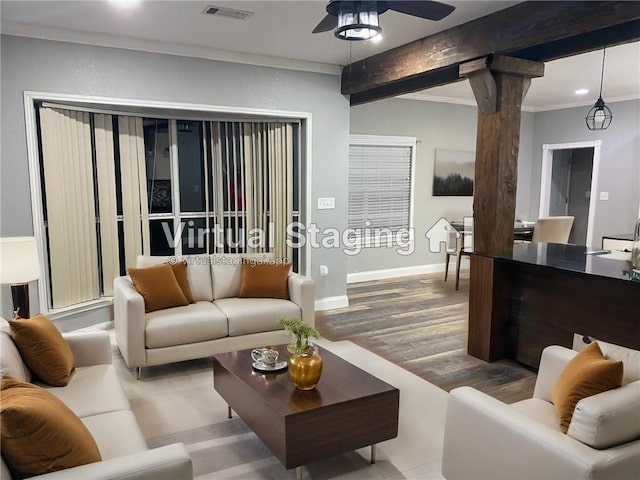 living area featuring decorative columns, visible vents, baseboards, ornamental molding, and wood finished floors