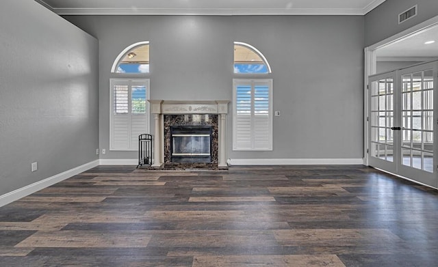 unfurnished living room featuring french doors, dark hardwood / wood-style flooring, ornamental molding, a fireplace, and a high ceiling