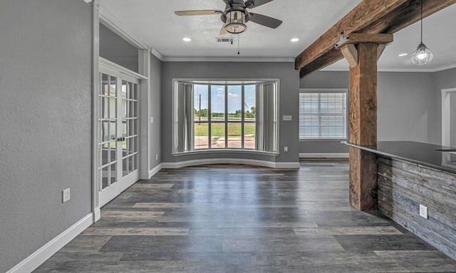 unfurnished living room with a textured wall, dark wood-type flooring, visible vents, baseboards, and crown molding