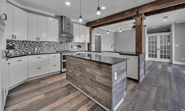 kitchen with beamed ceiling, wall chimney exhaust hood, decorative light fixtures, and french doors