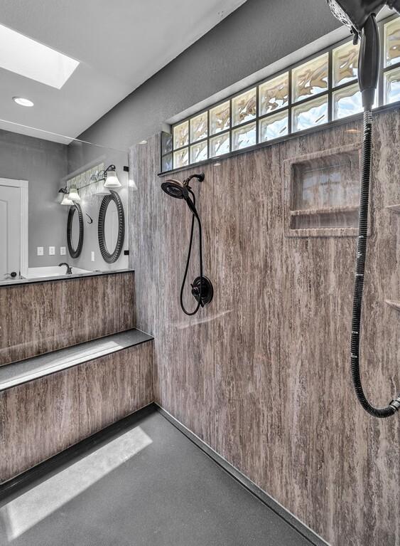 interior details featuring a skylight, concrete floors, tiled shower, and vanity