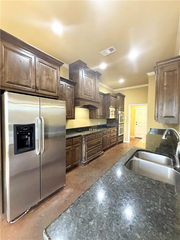 kitchen featuring crown molding, visible vents, appliances with stainless steel finishes, a sink, and dark brown cabinetry