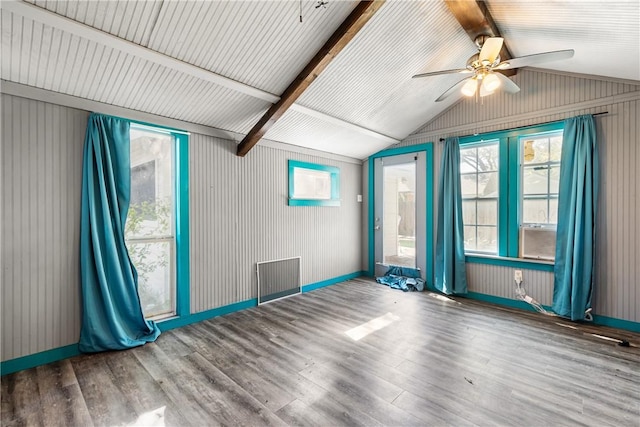 spare room featuring lofted ceiling with beams, ceiling fan, wood-type flooring, and wooden walls