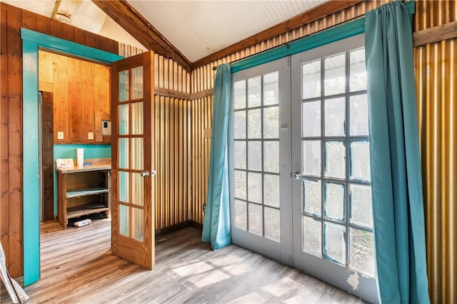 doorway to outside with wood walls, french doors, lofted ceiling with beams, and light hardwood / wood-style floors