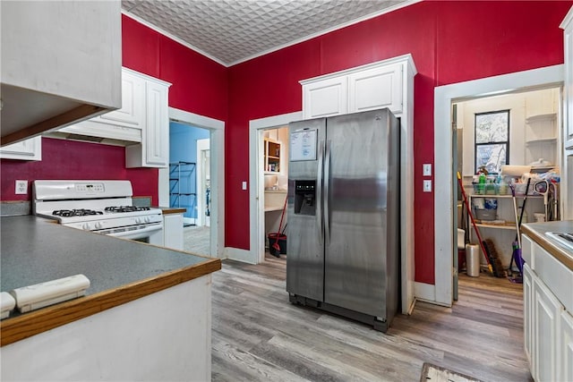 kitchen featuring white gas range, stainless steel fridge, and white cabinets