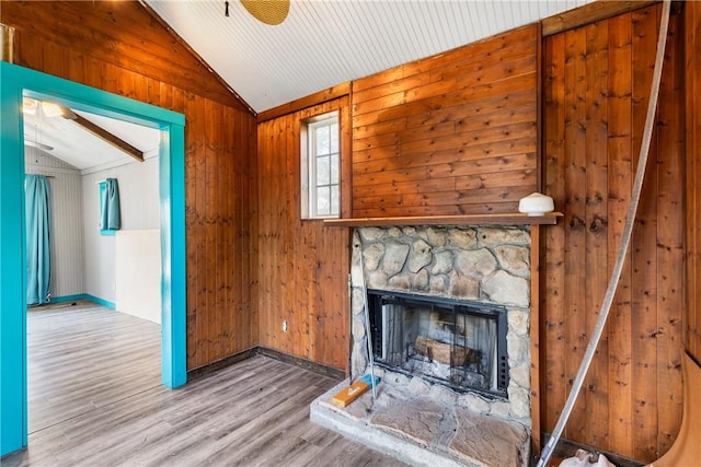 unfurnished living room with a fireplace, light hardwood / wood-style flooring, vaulted ceiling, and wood walls