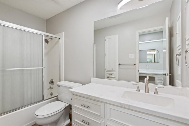 full bath featuring combined bath / shower with glass door, toilet, and vanity