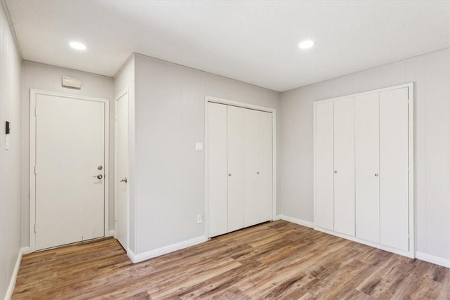 unfurnished bedroom with recessed lighting, wood finished floors, and baseboards