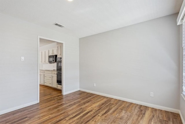 unfurnished room featuring visible vents, baseboards, and wood finished floors