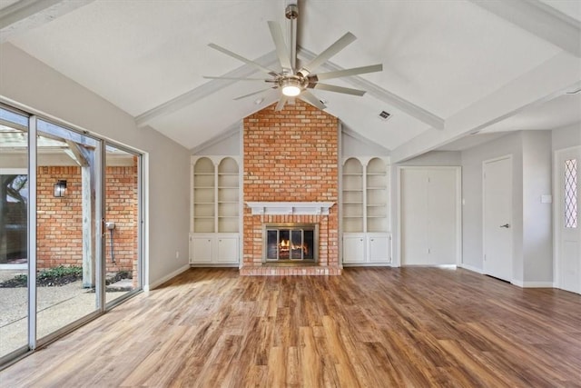 unfurnished living room with a brick fireplace, vaulted ceiling with beams, a ceiling fan, and light wood finished floors