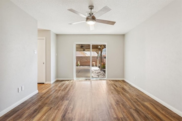 empty room with wood finished floors, baseboards, and a textured ceiling